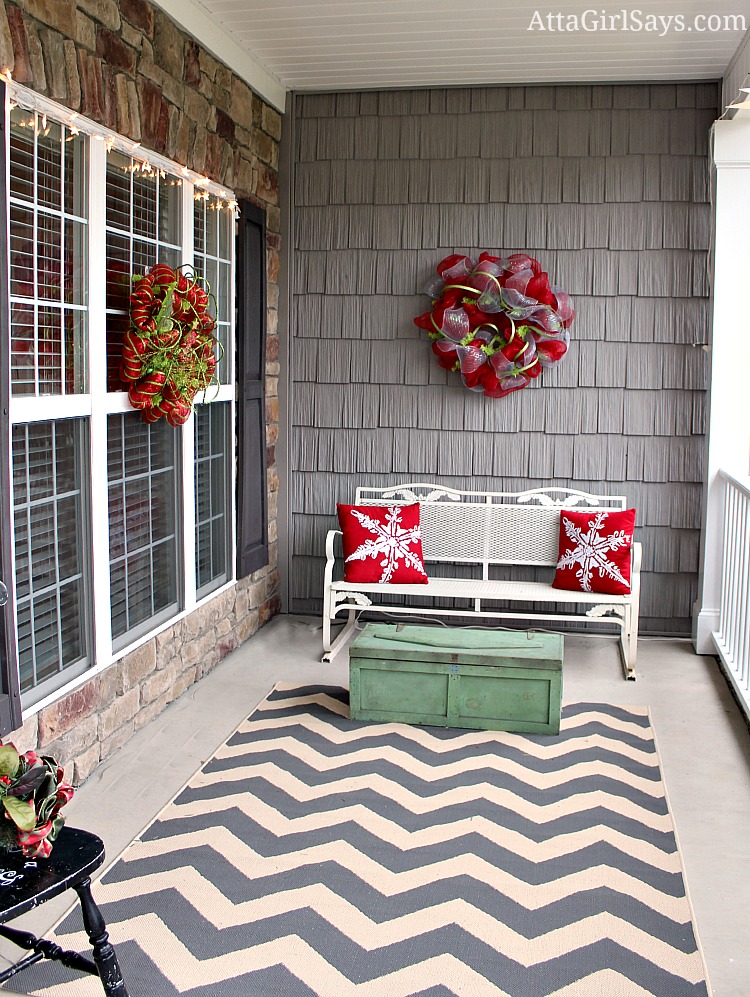 side porch decorated for Christmas with snowflake pillows and gray chevron rug and antique toolbox