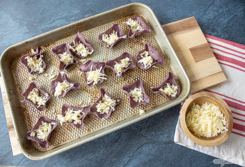 blue corn scoop tortilla chips filled with cheese and roasted garlic on a sheet pan