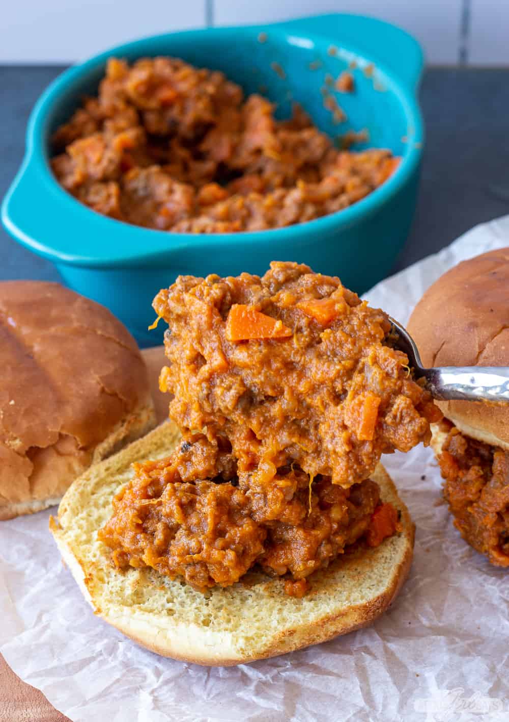 spoon healthy Sloppy Joes filling onto a toasted bun
