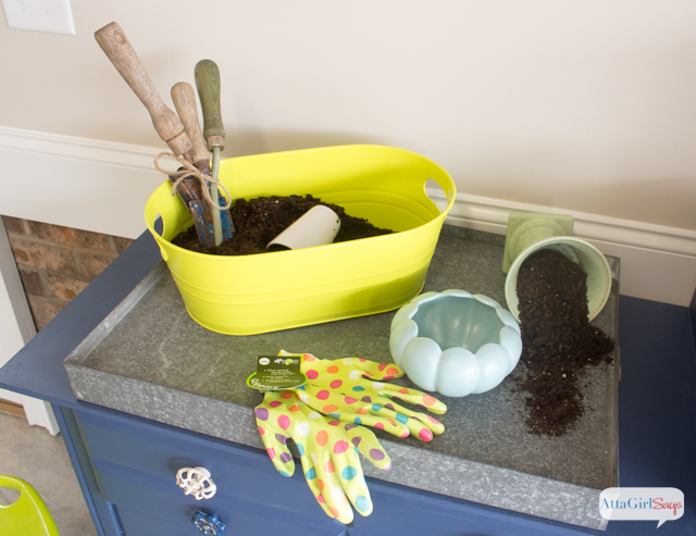 galvanized metal tray with pot, gloves and a dirt bucket on a garden table