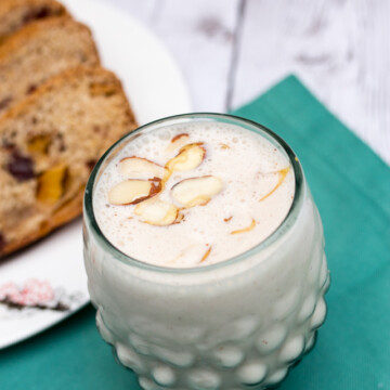 smoothie in a hobnail glass garnished with sliced almonds