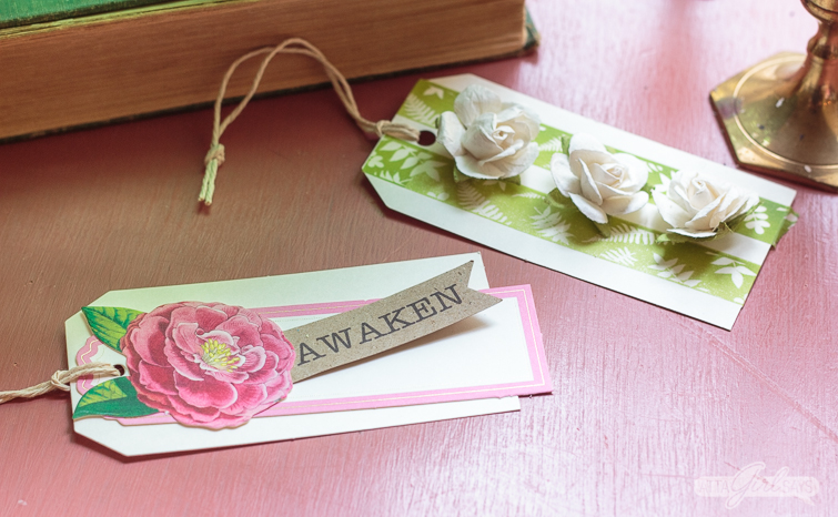 two handmade spring gift tags on a pink table