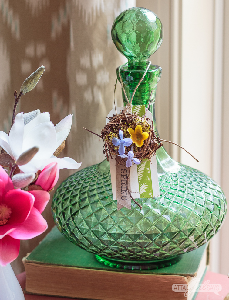 bird's nest on a spring tag hanging on a green glass bottle