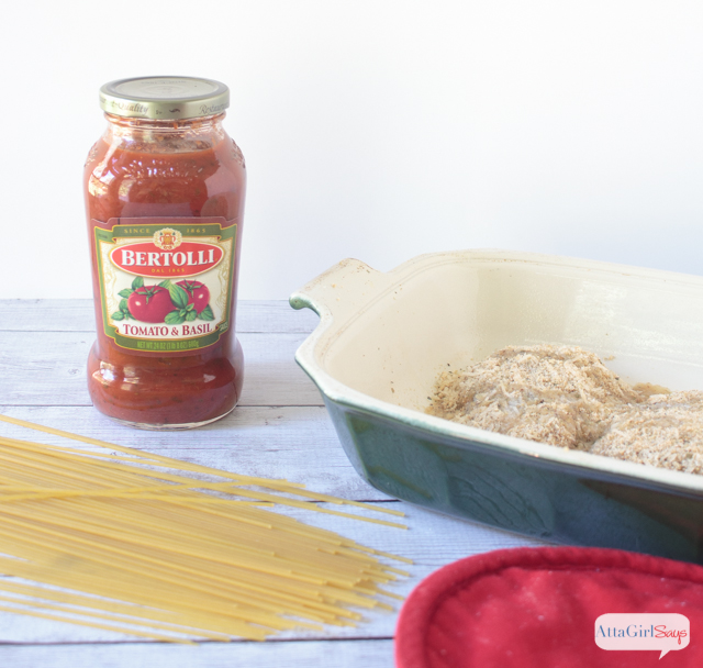 jar of pasta sauce beside a dish of breaded parmesan chicken breasts