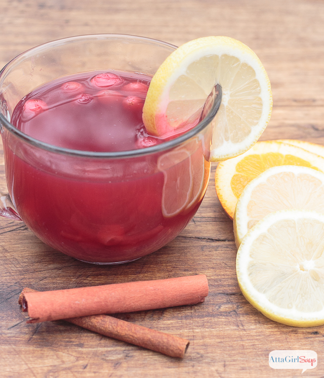 mug of spiced cranberry tea with lemon garnish and cinnamon sticks