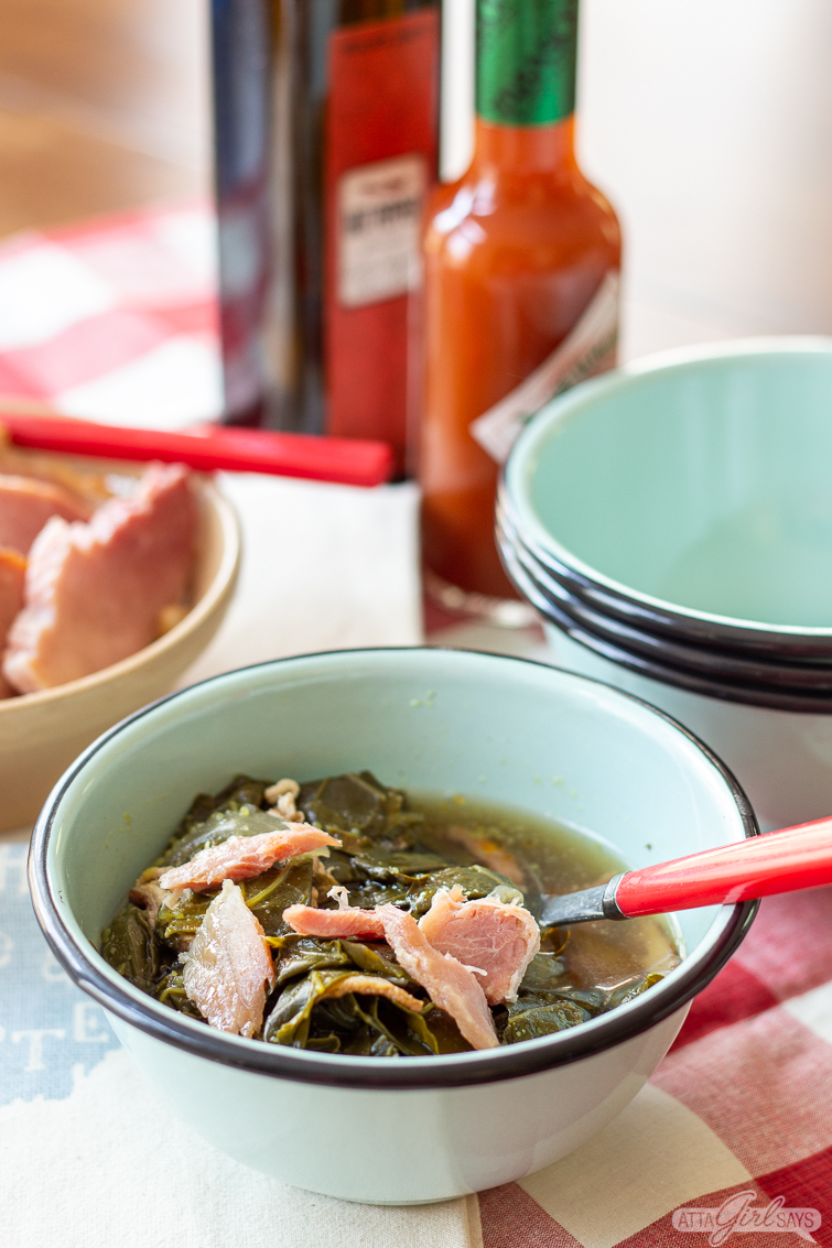 bowl of collard greens and ham with hot sauce and vinegar