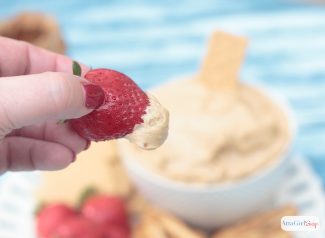 dipping a strawberry into cream cheese cookie butter dip