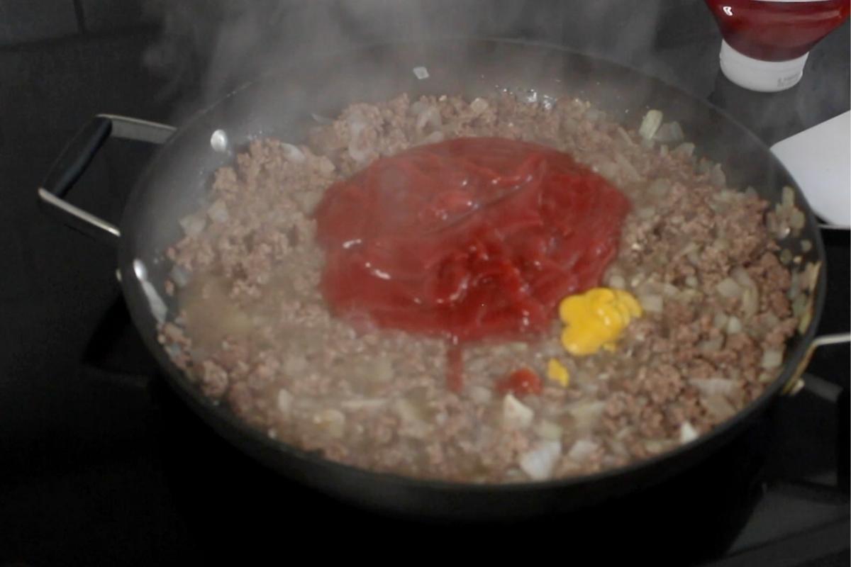 adding ketchup and mustard to homemade hot dog chili