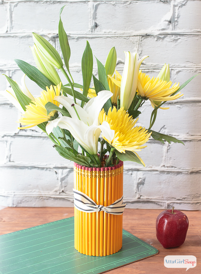 Welcome your favorite teacher back to school with a thoughtful, homemade teacher appreciation gift. This vase is made from dozens of No. 2 pencils affixed to a glass vase. Add a bouquet of gorgeous white lilies and yellow mums. And don't forget an apple!
