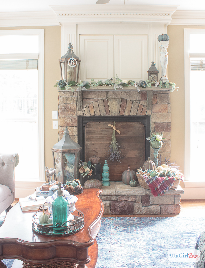 A cozy plaid blanket scarf inspired my fall fireplace mantel decor. Rather than traditional orange and yellow, I decorated with pops of aqua, indigo and purple. Be sure to click to see more gorgeous fall mantels.