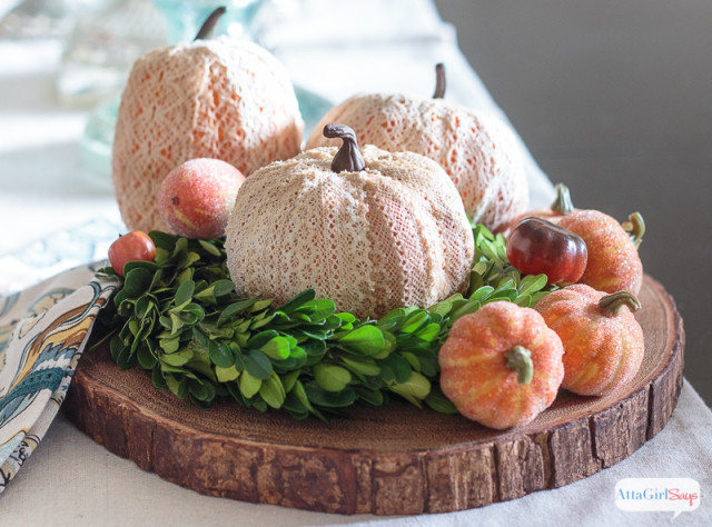 lace pumpkins and greenery on a wood slice