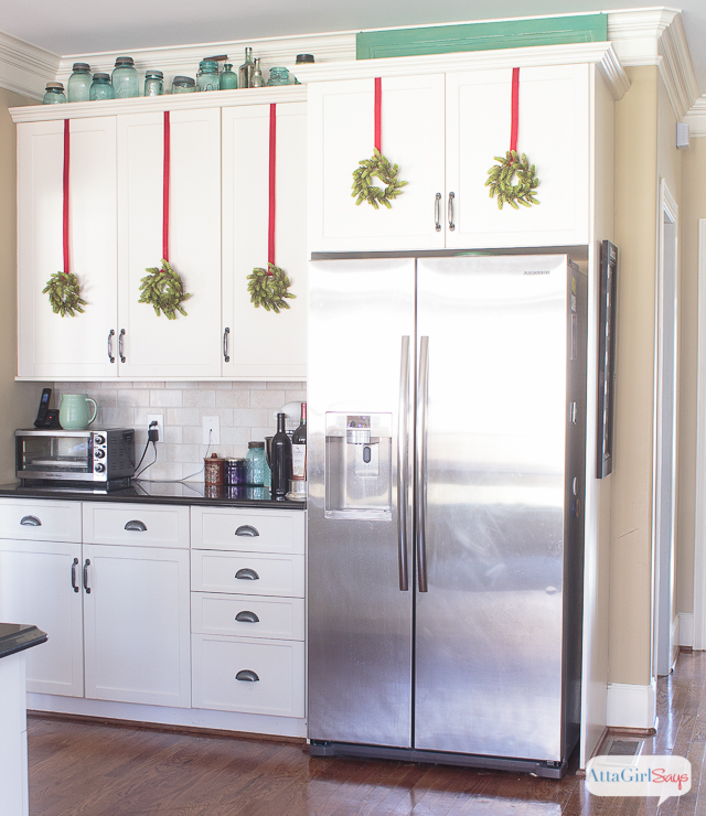 stainless steel refrigerator in a kitchen with black granite countertops and white cabinets