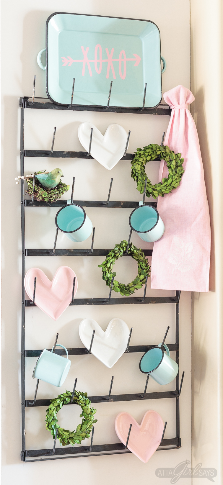 Dress up your coffee mug wall rack with simple Valentine's Day decor, including a "Gossip Girl" inspired quote you can make with your Cricut. Enamel coffee mugs, miniature boxwood wreaths and heart-shaped plates! Swoon. Click for sources to recreate this look! #mugrack #valentinesday #gossipgirl #xoxo #farmhouse #aquaandpink #mugrackmonday #valentinesdecor #cricutmade #cricutmaker #cricutexploreair #quotes