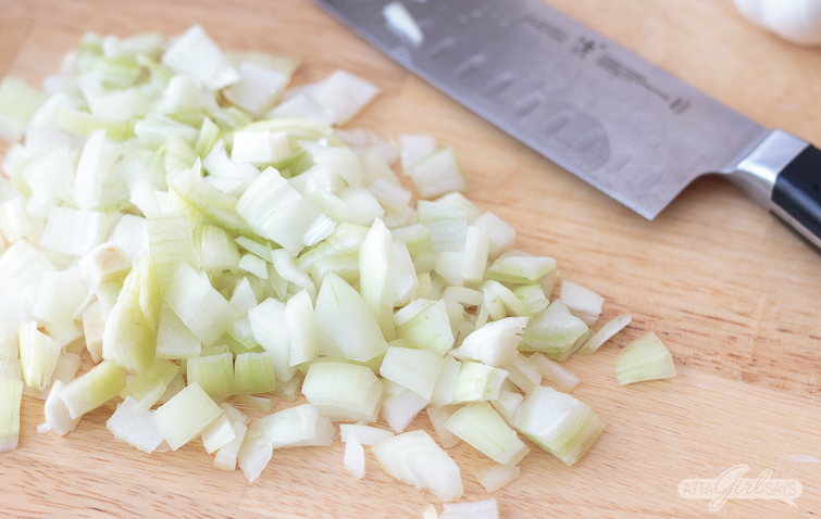 diced onions on a cutting board with a chef's knife