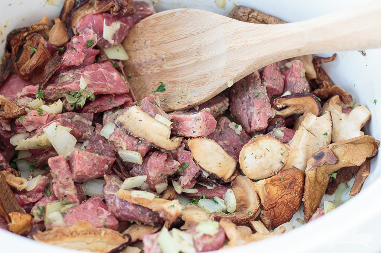 meat, mushrooms and onions in a slow cooker