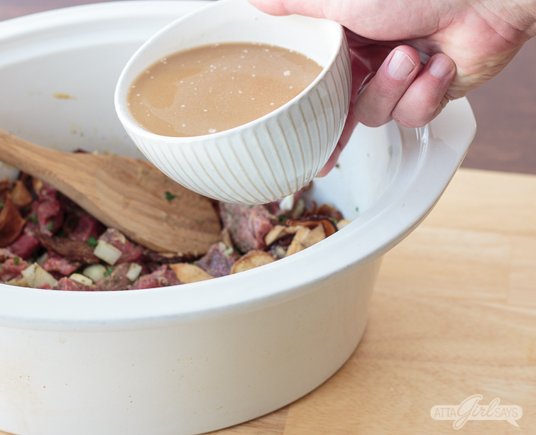 pouring thickened beef broth  over meat in a slow cooker