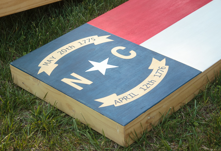 Create your own custom cornhole boards using colored stain and FrogTape. Click for the step-by-step directions on how to make this North Carolina state flag cornhole board design. #ad #cornhole #NCflag #yardgames #summerfun 