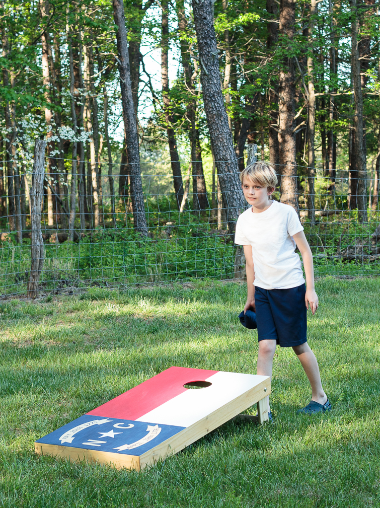 Create your own custom cornhole boards using colored stain and FrogTape. Click for the step-by-step directions on how to make this North Carolina state flag cornhole board design. #ad #cornhole #NCflag #yardgames #summerfun