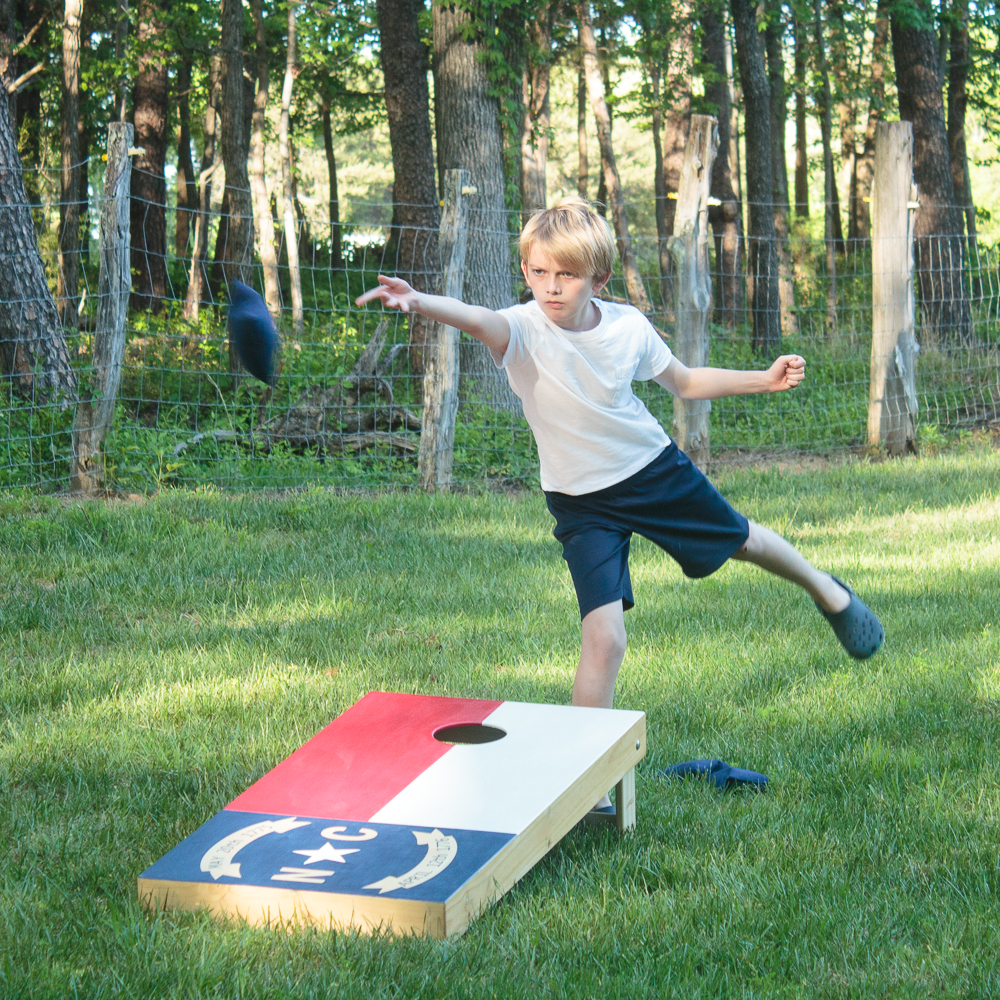 Create your own custom cornhole boards using colored stain and FrogTape. Click for the step-by-step directions on how to make this North Carolina state flag cornhole board design. #ad #cornhole #NCflag #yardgames #summerfun 