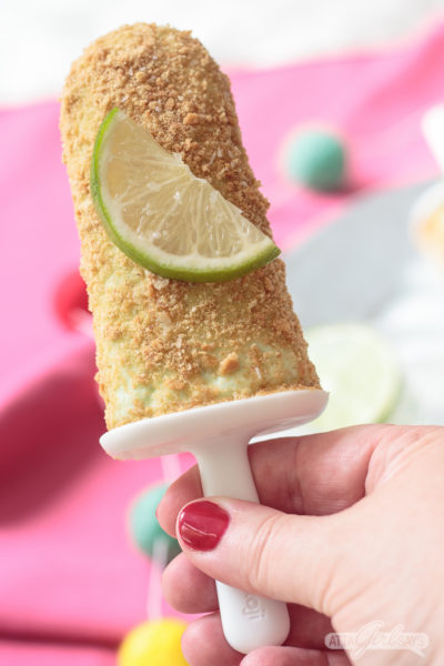 Closeup photo of a crumb-coated margarita popsicle with a lime slice on top of it.