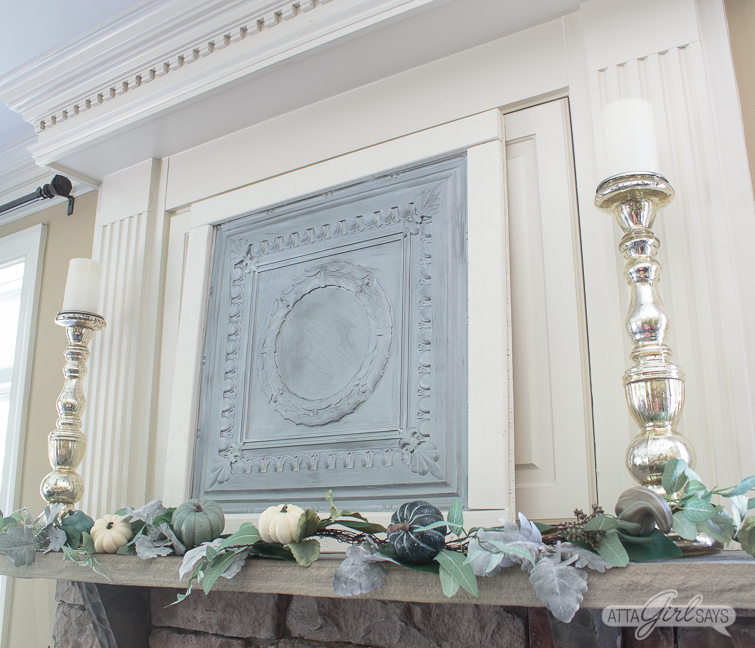 silver tin ceiling panel on a fireplace mantel, decorated with a silvery green fall garland and tall mercury glass candlesticks