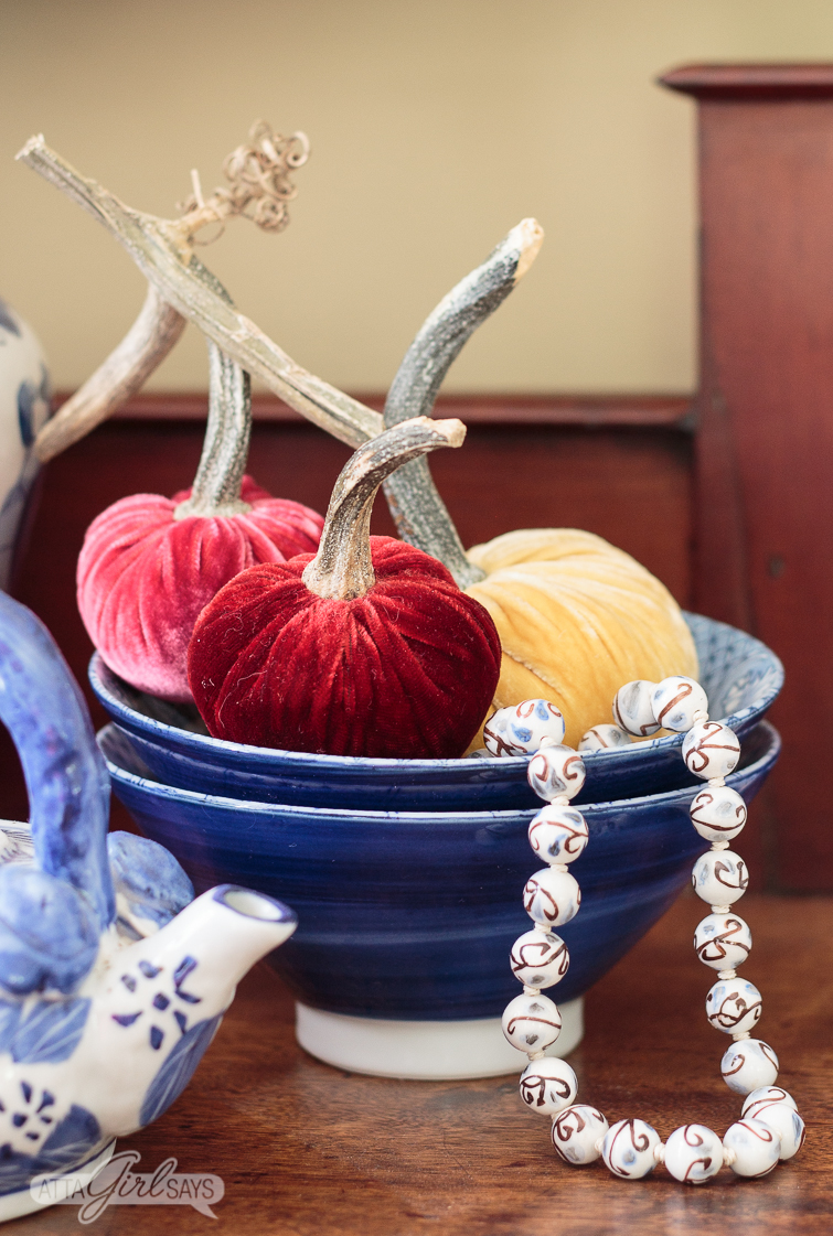 burgundy, mauve and gold velvet pumpkins in a blue bowl