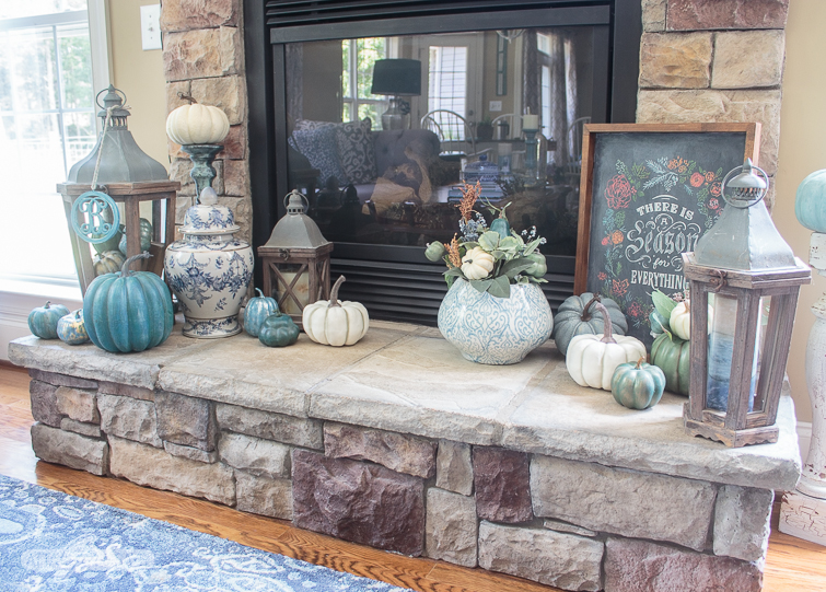 stone fireplace heart decorated for fall with chalkboard art, blue and white ginger jars and pottery and blue, white and aqua pumpkins