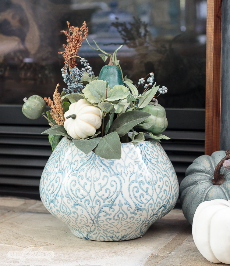 blue and white ginger jar vase filled with a fall floral arrangement with miniature white pumpkins