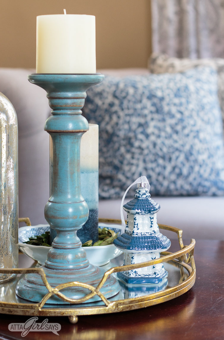 gold mirrored tray on a coffee table with a blue candlestick and a Chinese pagoda ornament sitting on it