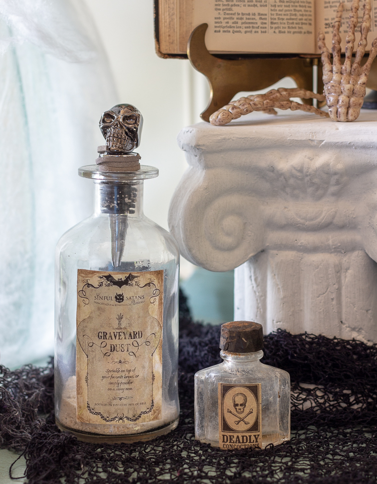Halloween spell bottles on black creepy cloth atop a vintage painted buffet