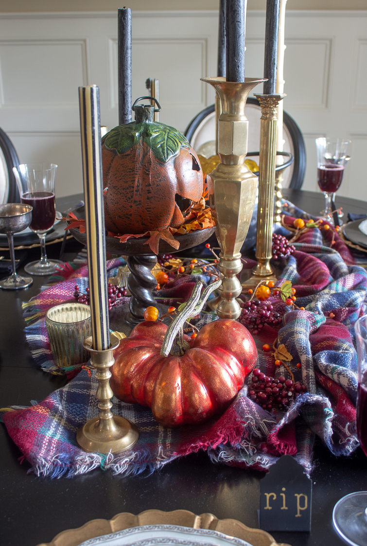 antique brass candlesticks on a fall harvest Halloween dining table with orange metallic pumpkins and a plaid blanket scarf tablecloth
