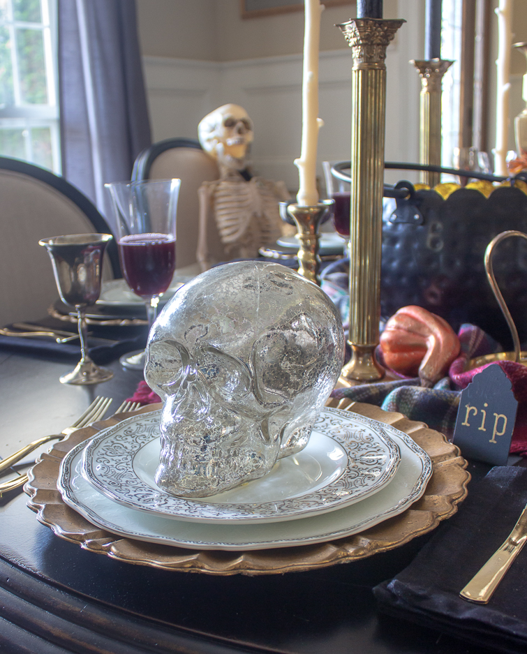 silver mercury glass skull on silver and white china as part of Halloween table decorations