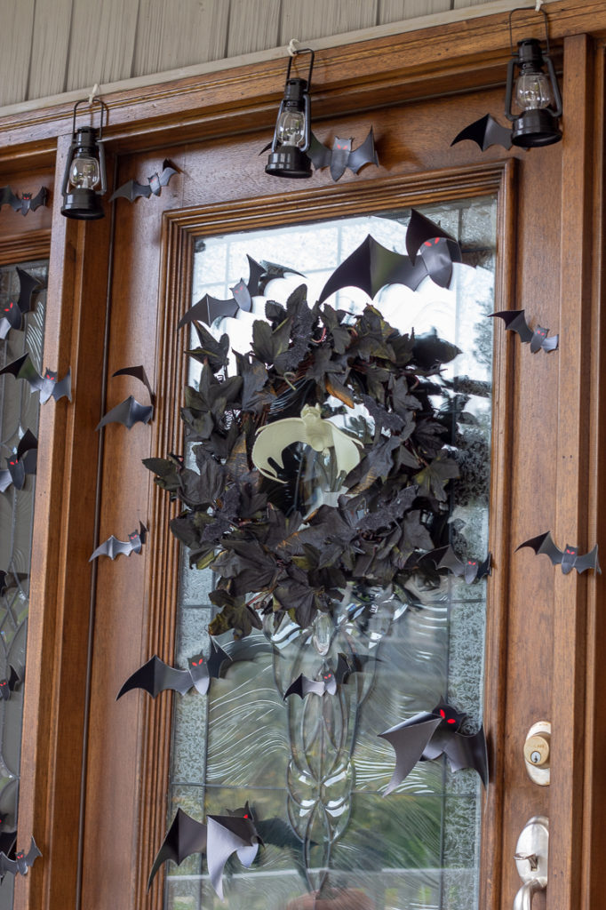 black maple leaf wreath and paper bats on a front door