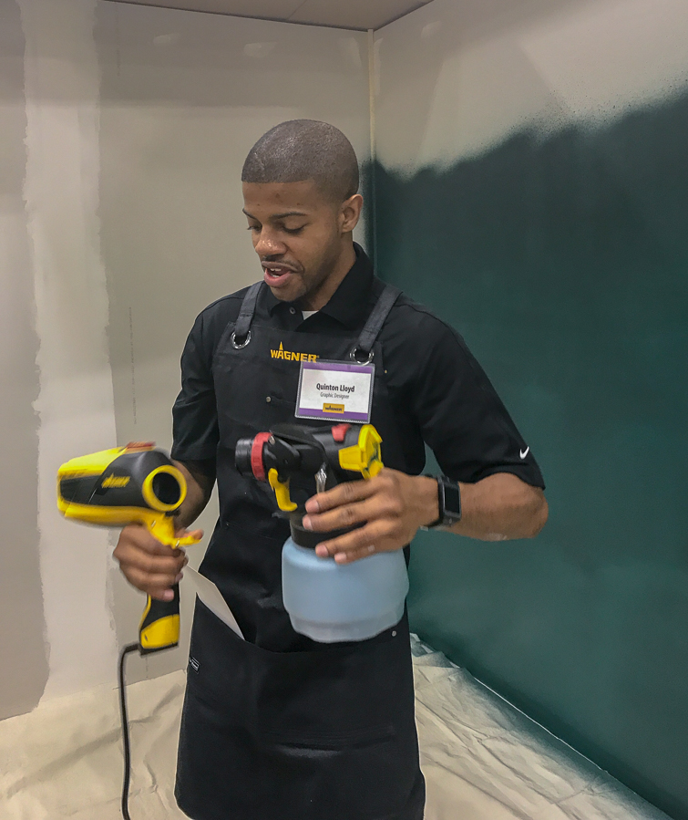 man holding a paint sprayer in a half-painted room