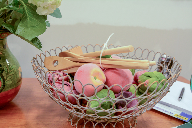 wire bowl with peaches, artichokes and wooden spoons in it