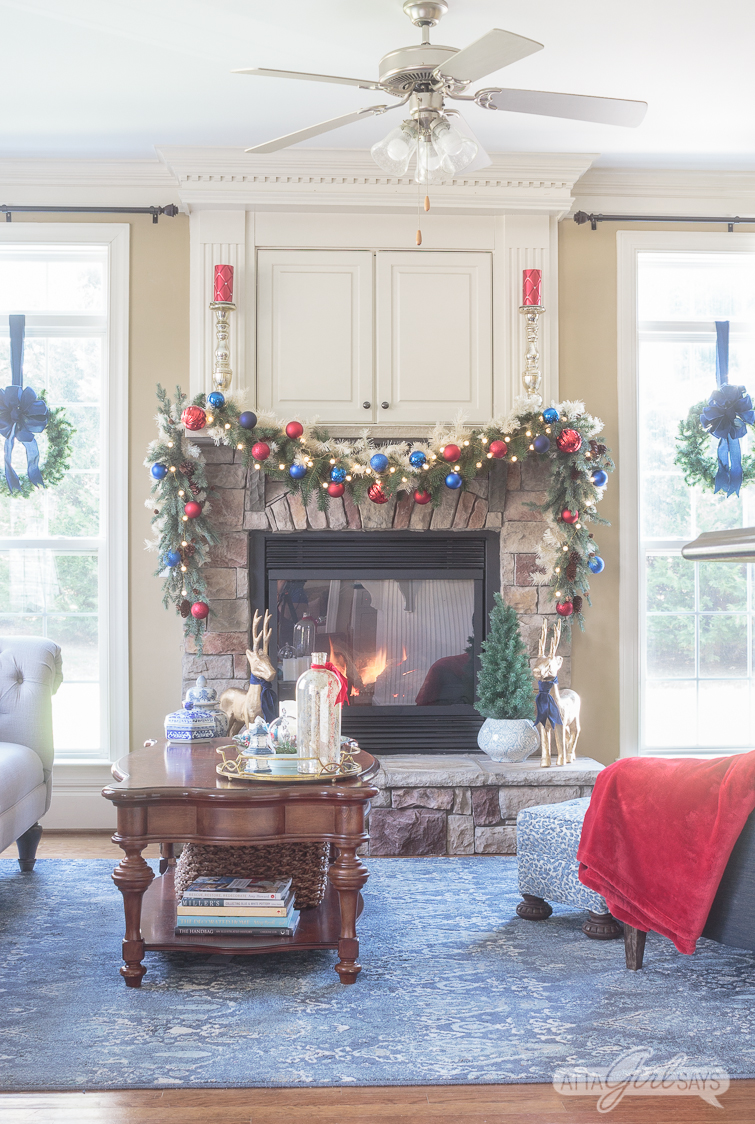 stone fireplace hearth and mantel decorated for Christmas with a red and blue garland