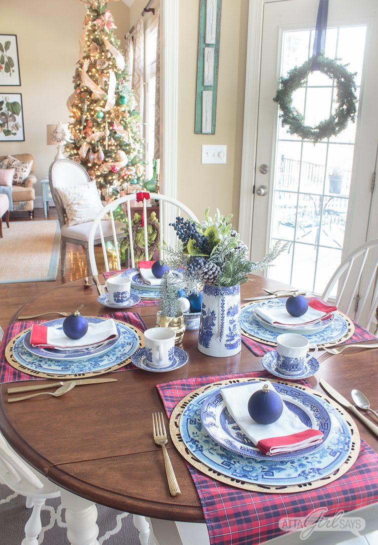 Breakfast table set with blue and white dishes for Christmas with a Christmas tree in the background