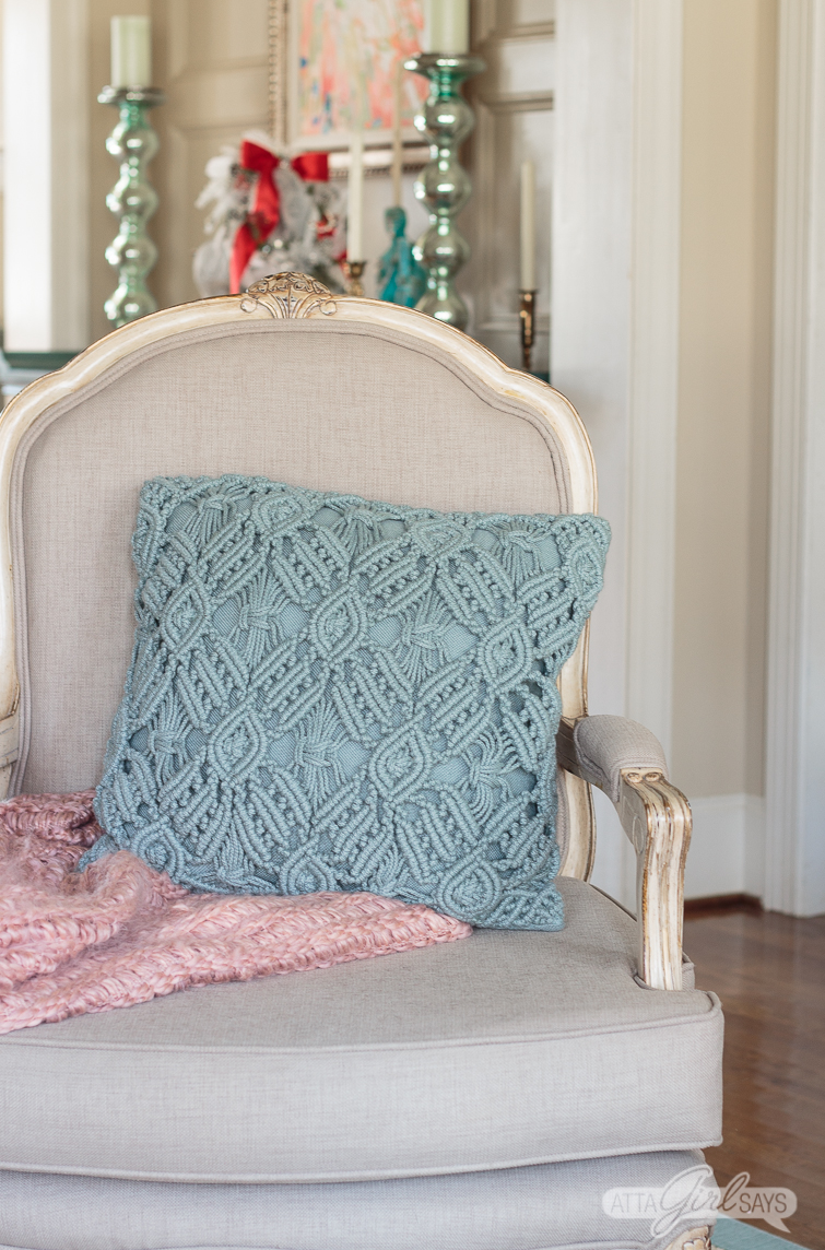 French bergere chair with a pink throw blanket and an aqua pillow on it