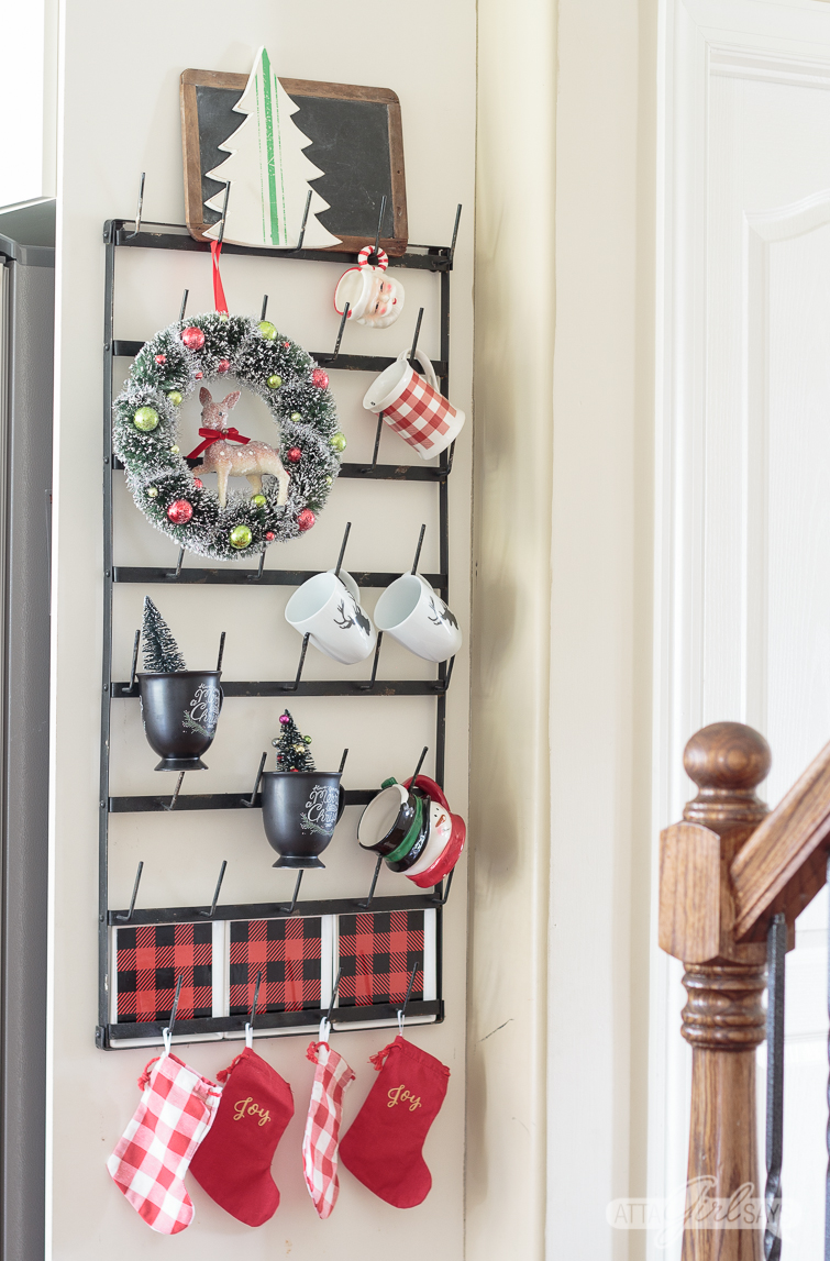 Christmas mug rack decorated with mugs, buffalo check plates and a vintage wreath