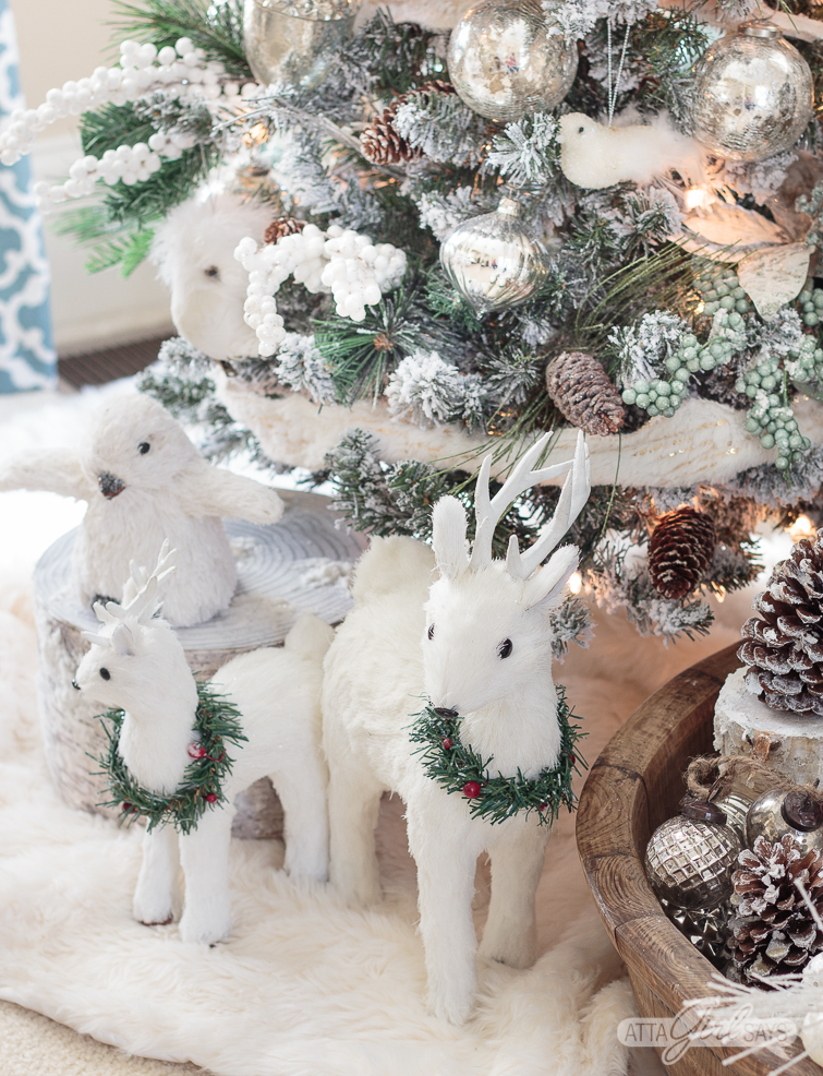 white deer at the base of a woodland Christmas tree