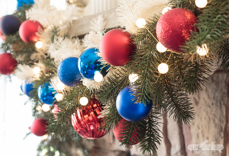 green and white Christmas garland decorated with red and blue ornaments and ball lights
