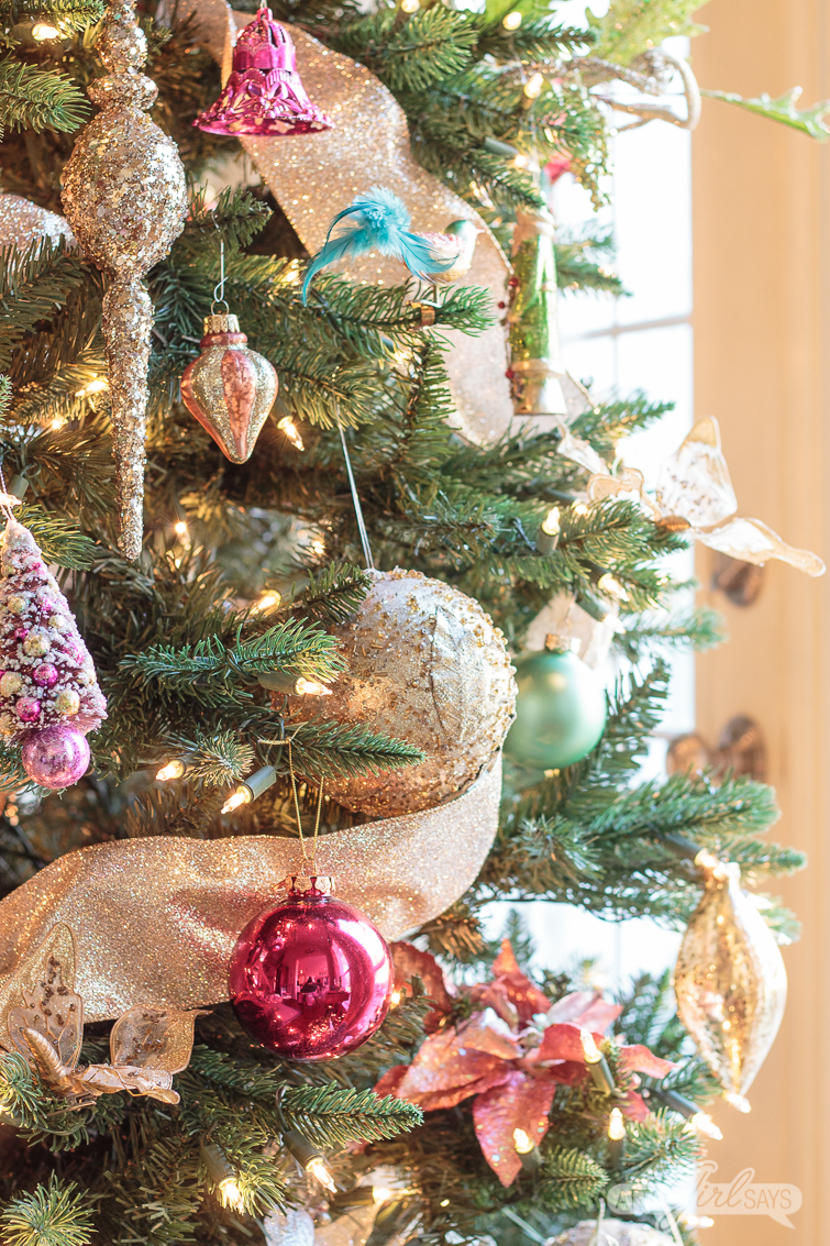 pink, green and gold ornaments on a Christmas tree decorated with gold ribbon