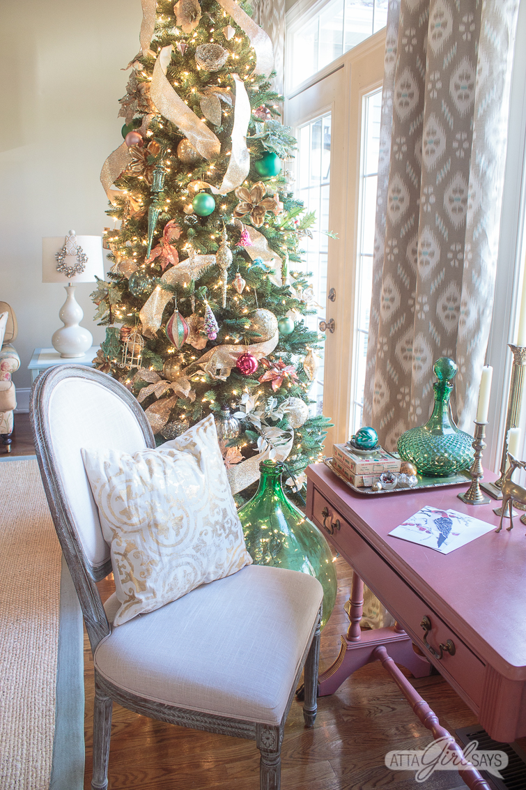 pink writing desk with green accessories and a beautiful Christmas tree in the background