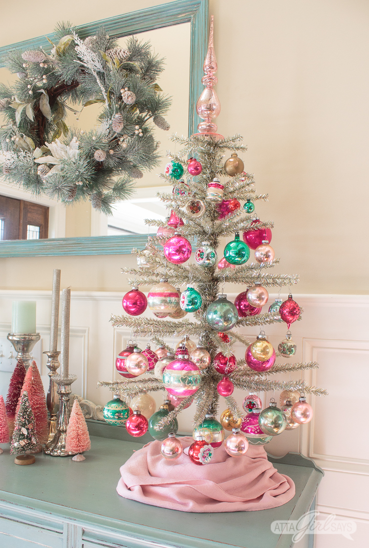 feather tinsel Christmas tree decorated with pink and green Shiny Brite ornaments on top of an aqua buffet