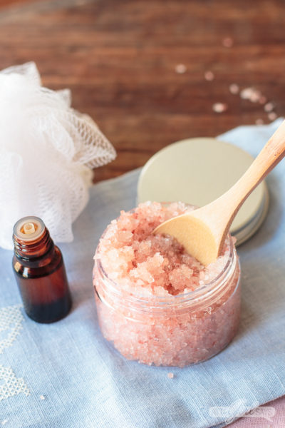 jar of pink Himalayan salt scrub and essentail on a blue towel