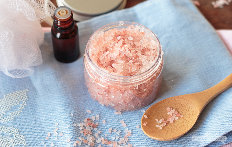 ylang ylang essential oil and pink Himalayan salt scrub on a blue towel