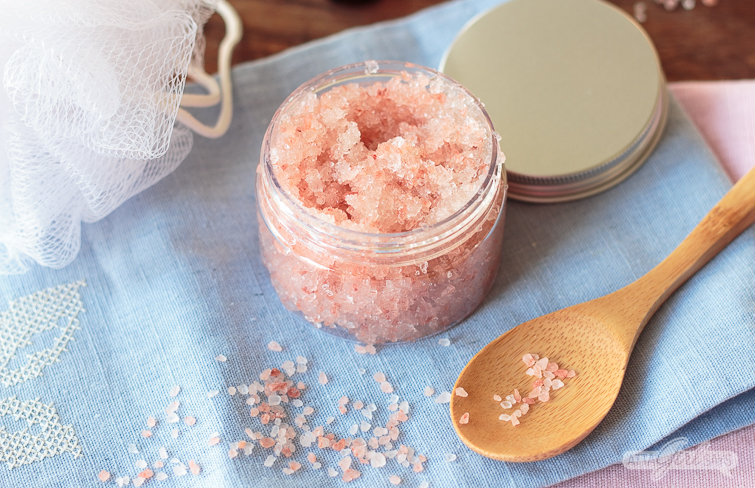 jar of pink Himalayan salt scrub on a blue towel