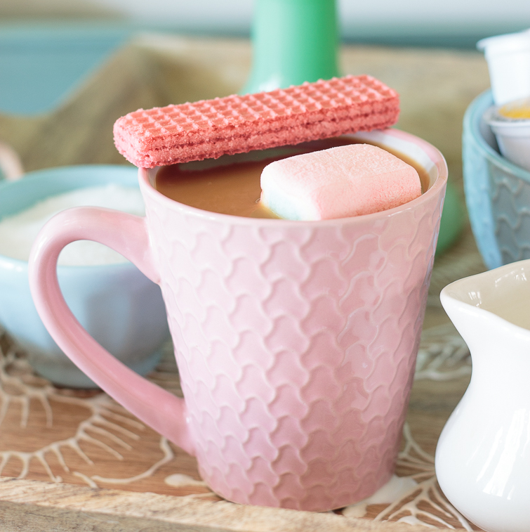 coffee in a pink mug with a pink marshmallow and cookie wafer
