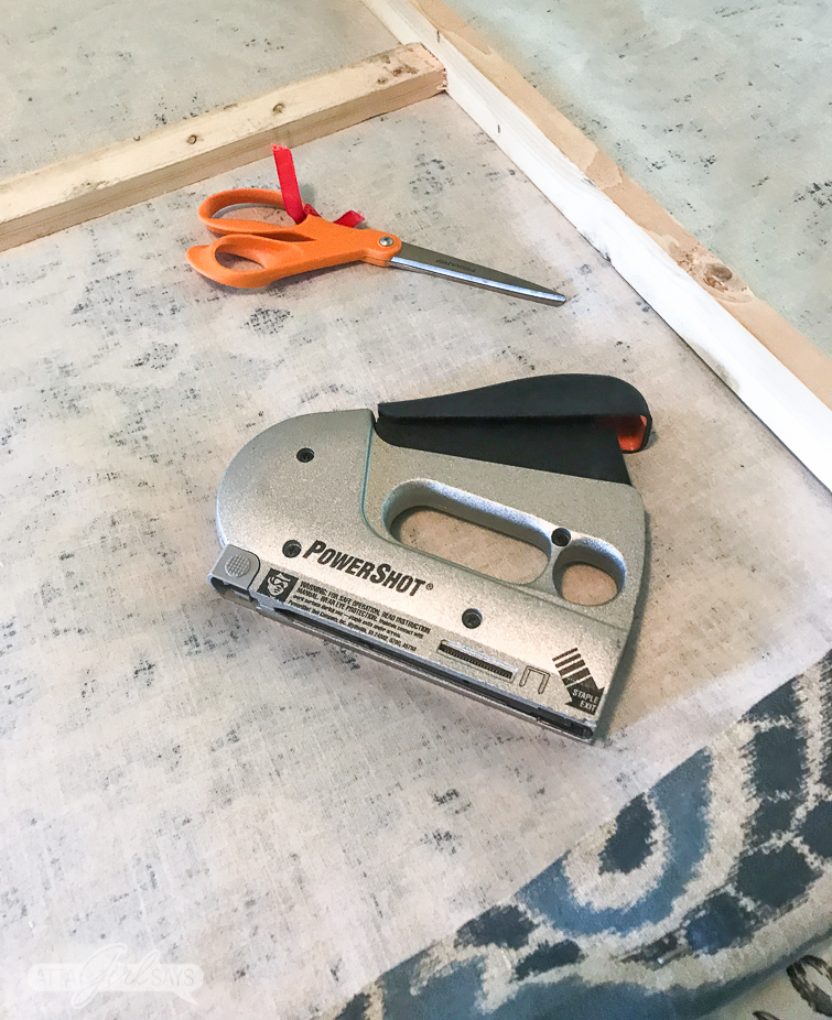 stapling designer fabric to a wooden frame to create oversized canvas art