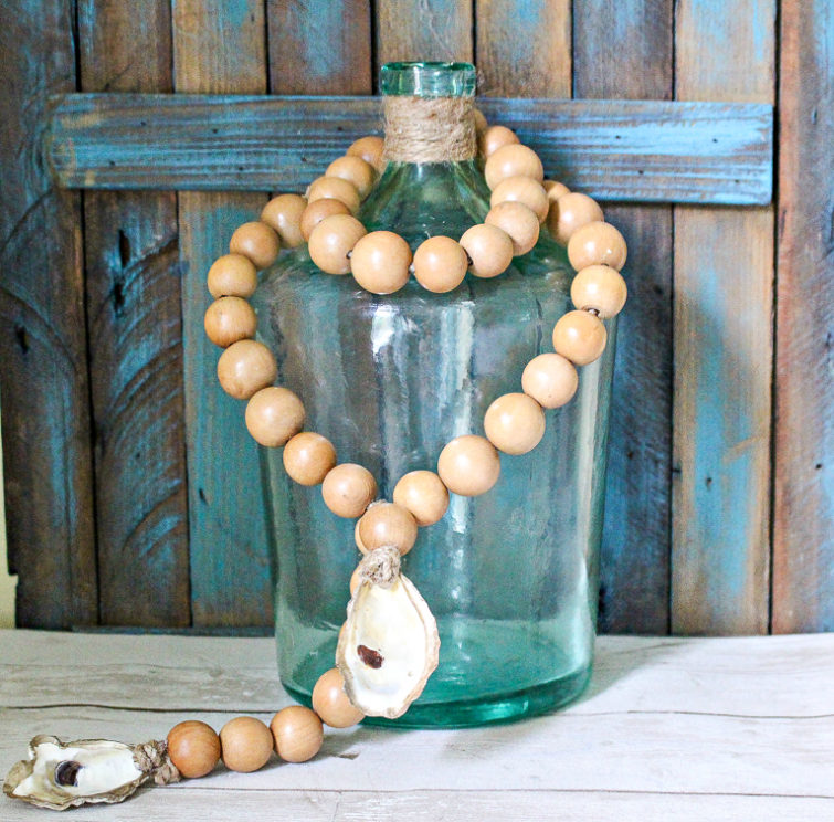 wooden beads with an oyster shell draped on a blue demijohn